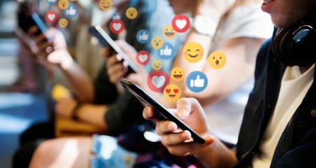 People on their phones responding to social media using emojis
